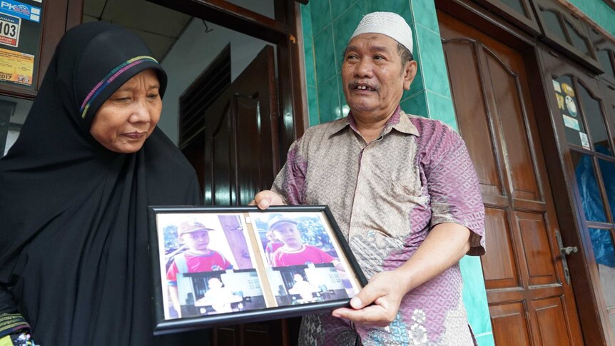 Setijoko and his wife hold framed photographs of Riky and Riko Prawoto, two twins from Indonesia's 'twin village'.
