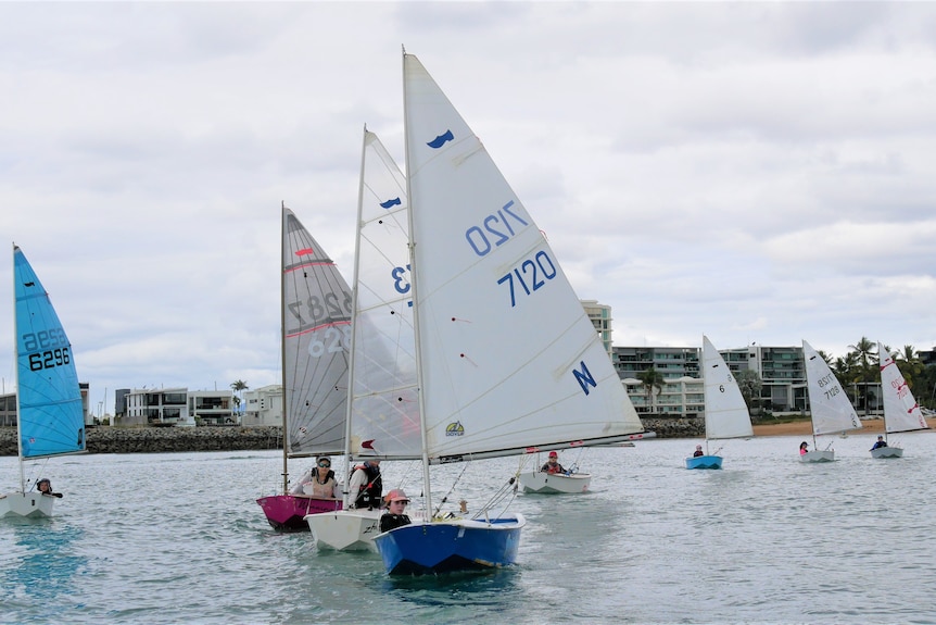 small sailing boats racing in the water, forming a symmetric line