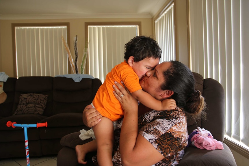 Megan Naden cuddles and kisses her two-year-old son Nayte at the Gomeroi gaaynggal centre in Tamworth.