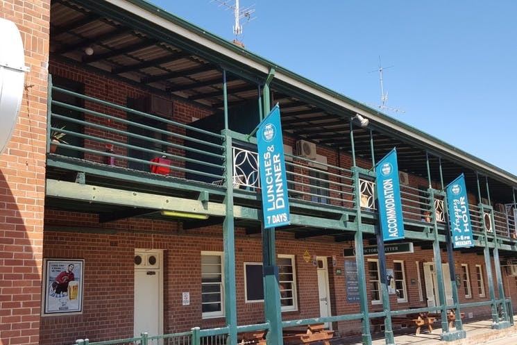 Exterior two storey brick hotel with banners advertising lunches, accommodation and happy hour