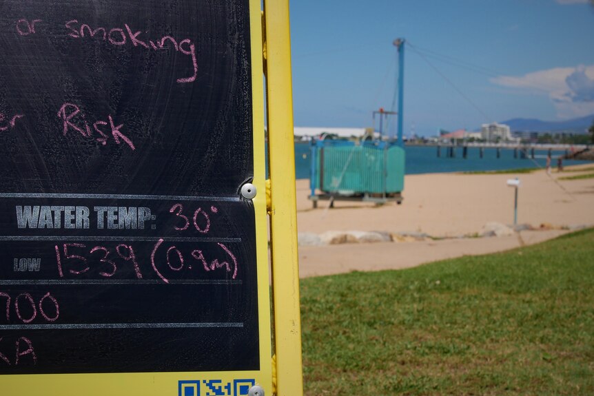 A chalkboard with in front of water with temperatures written on it