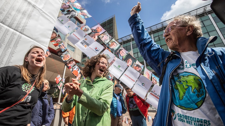 Environmentalists shout and pump the air with their fists to celebrate a victory outside court.