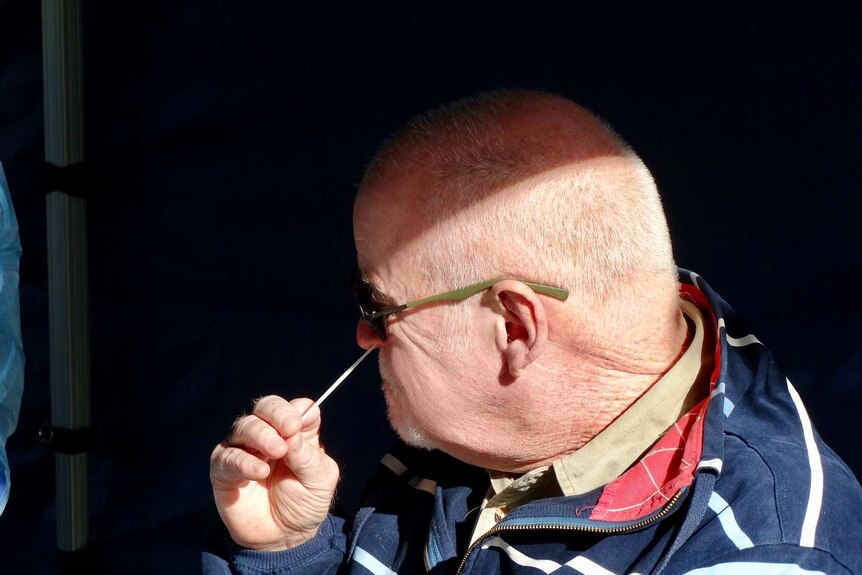 A man takes a swab from his nose.