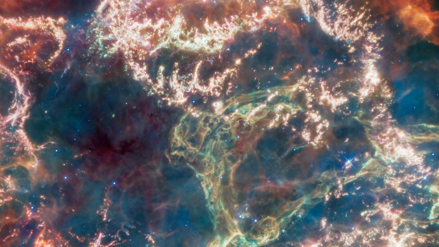 A zoomed-in shot of the image of Cassiopeia A, with green, red, pink, yellow and orange tinted illuminated shapes