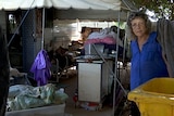 A woman stands outside her caravan with all her flood-damaged property