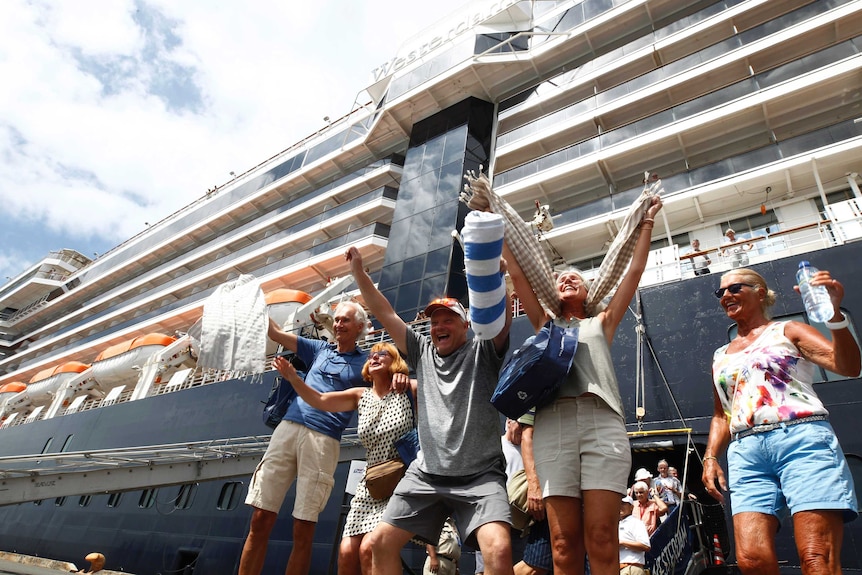 Passengers cheer as they disembark a ship