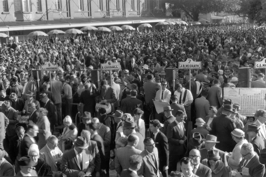 Crowds of people place bets in the bookie ring at Randwick Racecourse.