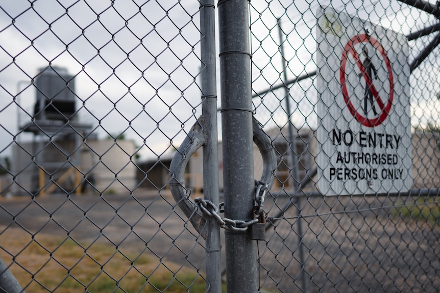 Locked metal gate with a no entry sign.