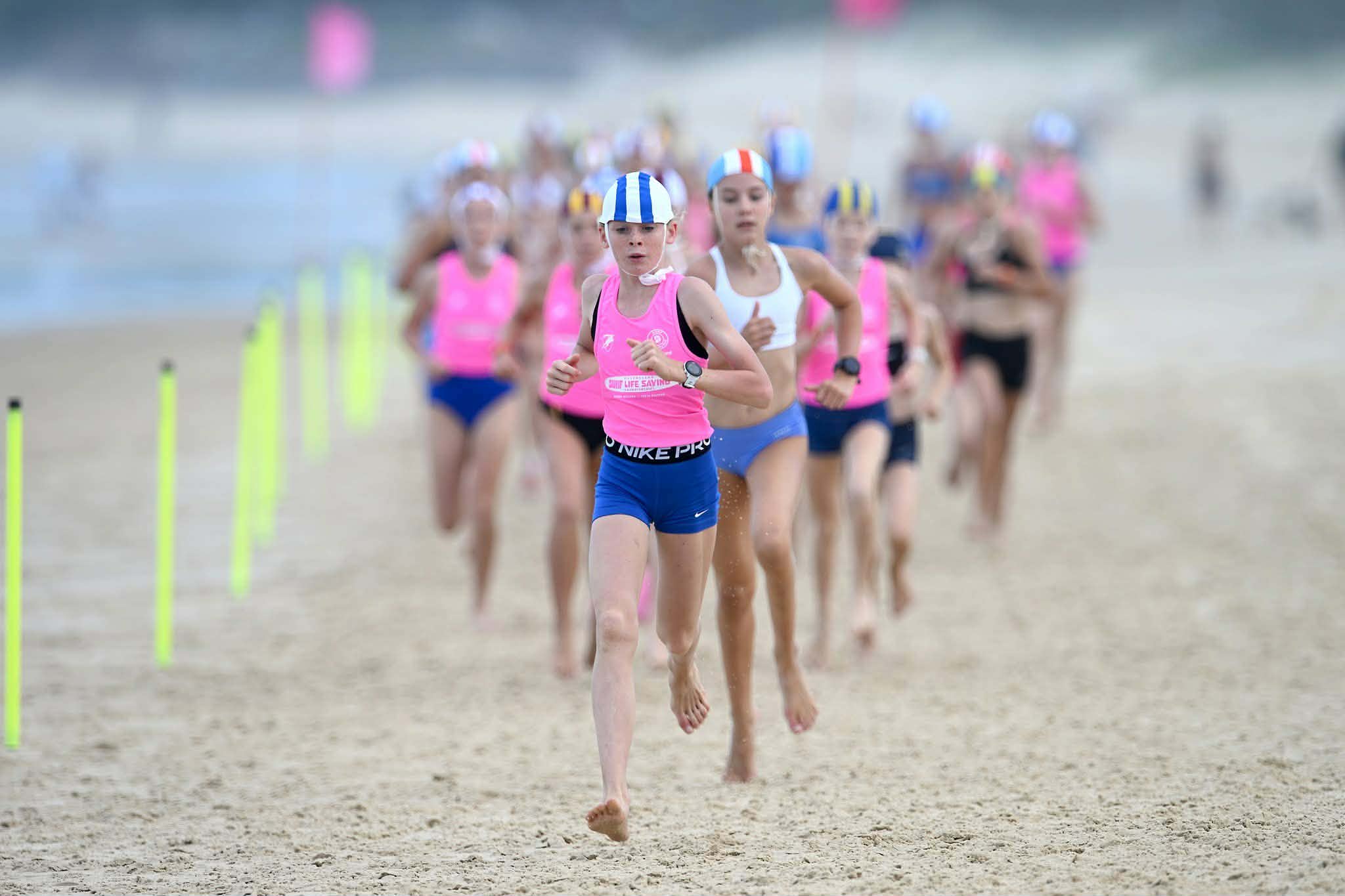 Chicas jóvenes en carrera de equipo de rescate de surf en la arena