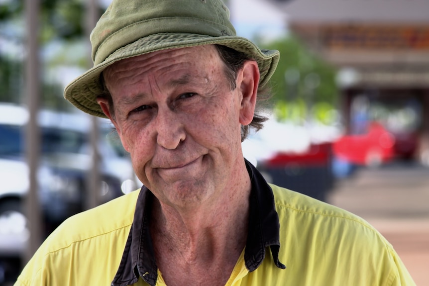 Image of middle-aged man wearing high-viz clothing and a bucket hat, half smiling. 