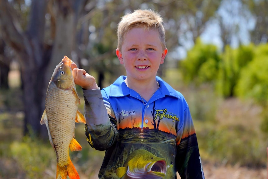A young boy holding a caught fish.