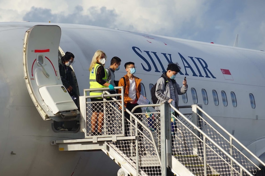 A Silk Air plane on the tarmac in Darwin with students disembarking down steel steps.