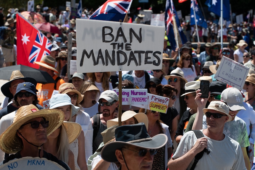 Protesters hold a 'ban the mandates sign'