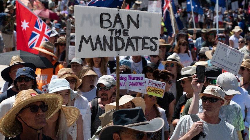 Protesters hold a 'ban the mandates sign'