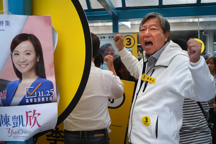 Pro-democracy candidate Lee Cheuk-yan shouts slogans next to an election poster.