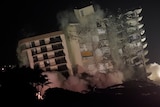 An already partially collapsed building is demolished at night. 