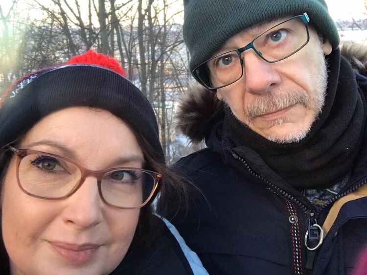 A woman and a man wearing glasses and beanies in a selfie.