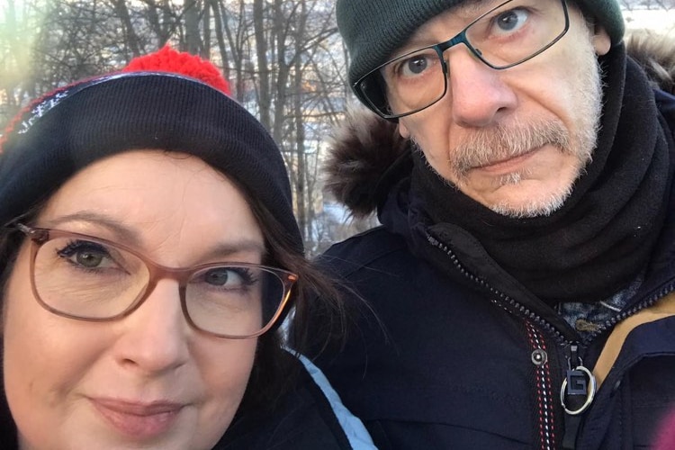 A woman and a man wearing glasses and beanies in a selfie.