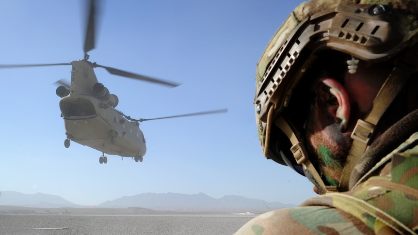 A soldier is seen from behind as a helicopter takes off in Afghanistan.