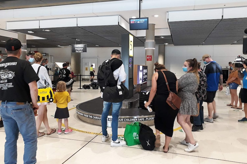 Travellers wait for luggage on baggage carousel on Brisbane airport.