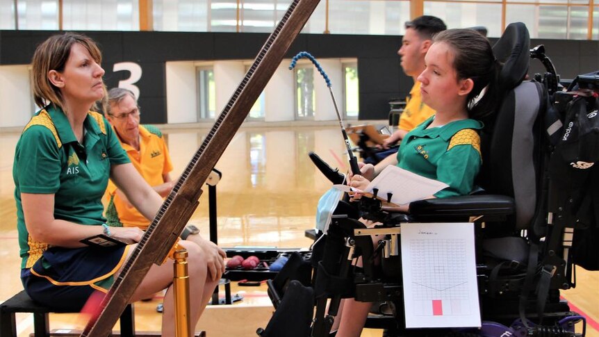 A mother sits in a chair looking across at her daughter who sits in a modified chair as they train for the Paralympics.