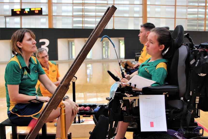 A mother sits in a chair looking across at her daughter who sits in a modified chair as they train for the Paralympics.