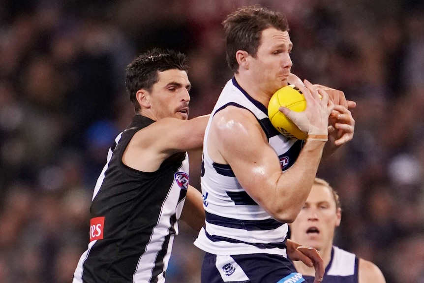 Geelong's Patrick Dangerfield marks a football on his chest ahead of Collingwood's Scott Pendlebury.