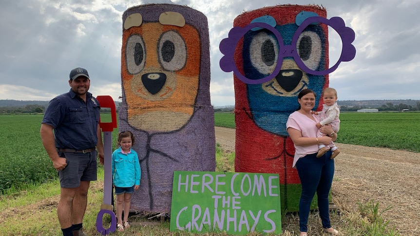 Family of four stand in front of haybales designed as characters from Bluey