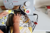 A woman's hands using a sewing machine to sew a blanket.