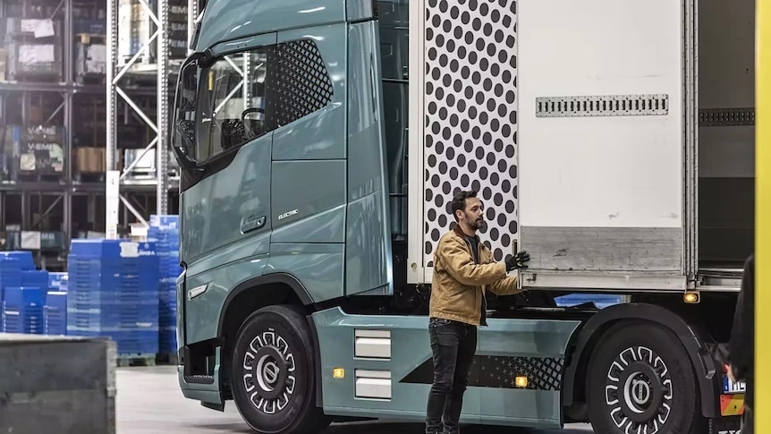 Man stands next to a Volvo EV truck in a warehouse.