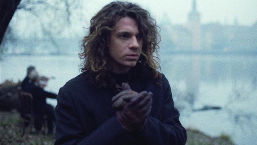 Michael Hutchence wears a coat and gloves in a screen-grab from Mystify
