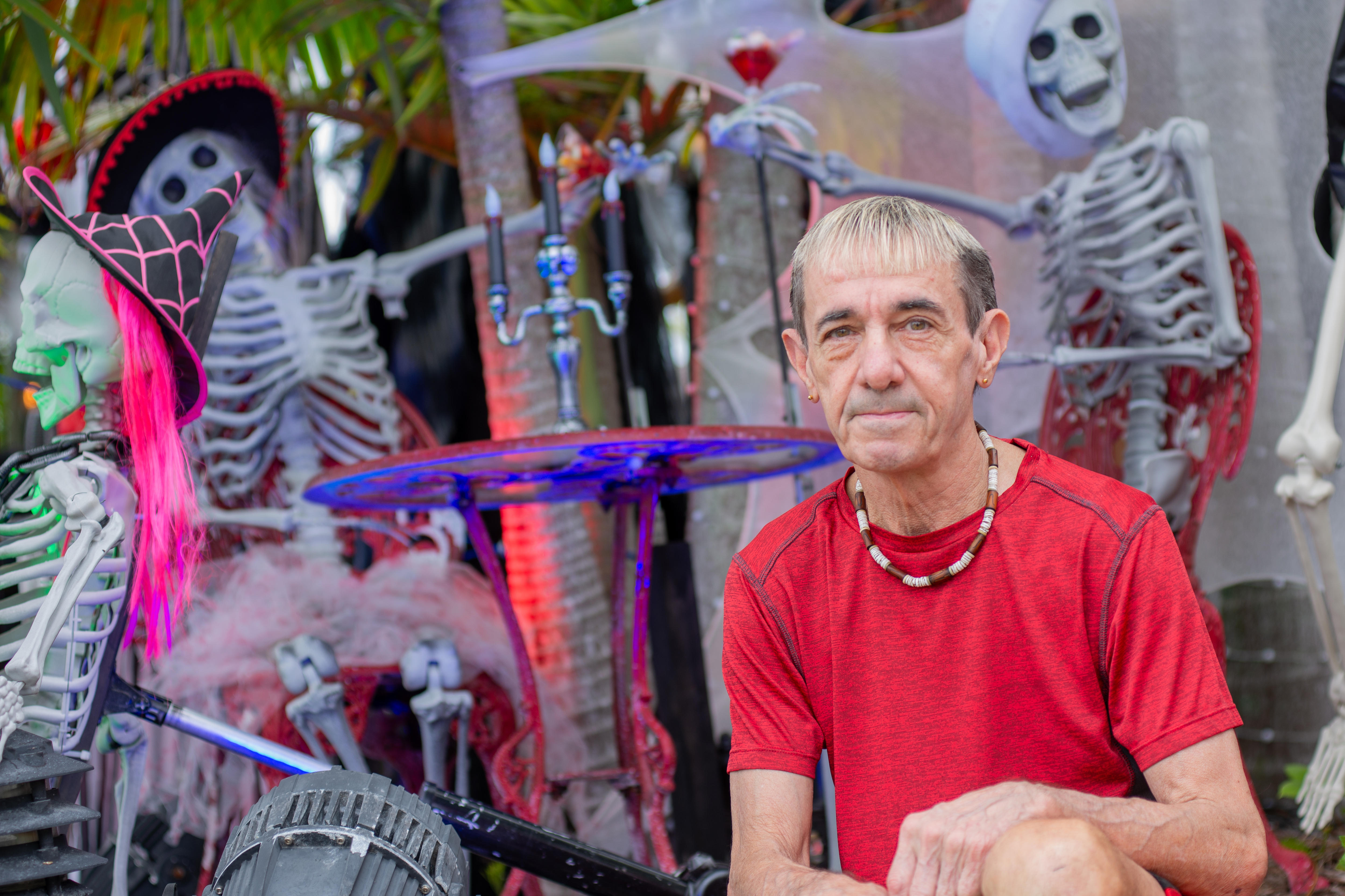 A man sits in front of a collection of Halloween skeletons.