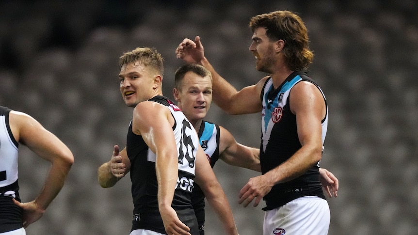 Three Port Adelaide players display joy and relief as they celebrate a win over the Western Bulldogs.
