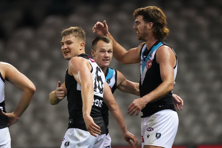 Three Port Adelaide players display joy and relief as they celebrate a win over the Western Bulldogs.