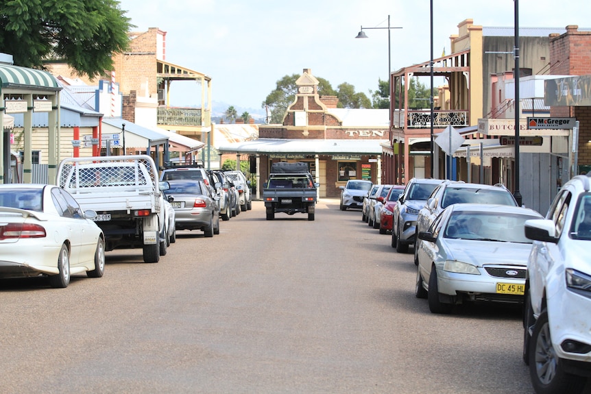 Street with cars parked along each side and ute driving down the centre