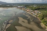 An aerial view shows an oil spill as it washes ashore near a beach-side town.
