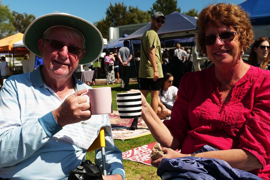 A man and a woman holding a coffee mug and smiling