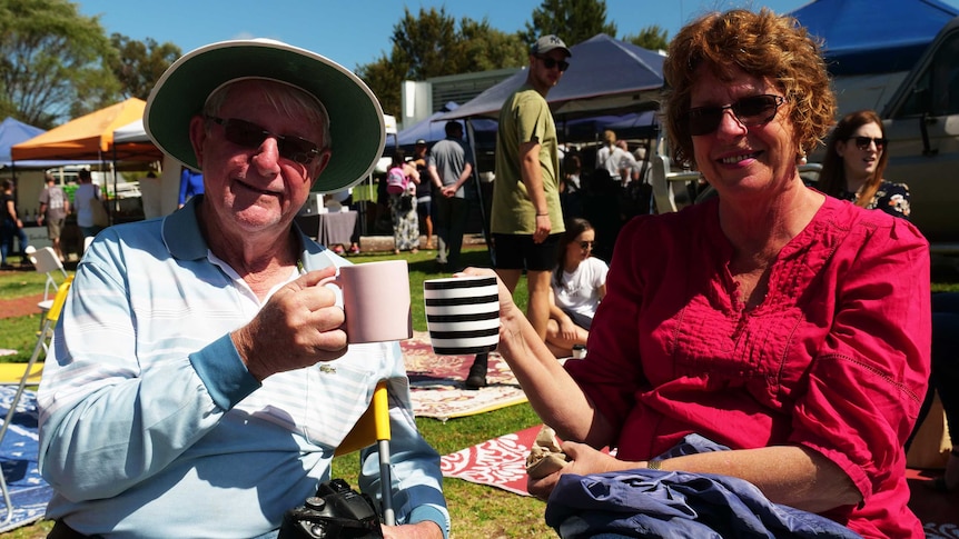 A man and a woman holding a coffee mug and smiling