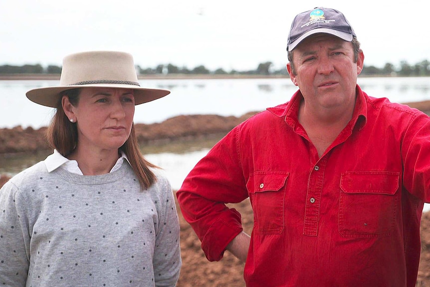 A woman and man stand on a field.