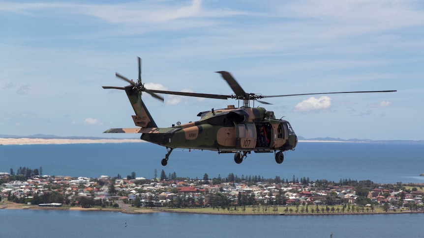A Black Hawk helicopter flies over Newcastle Harbour.