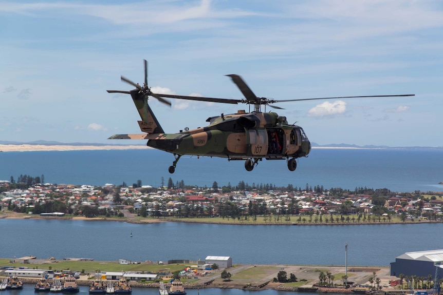 A Black Hawk helicopter flies over Newcastle Harbour.