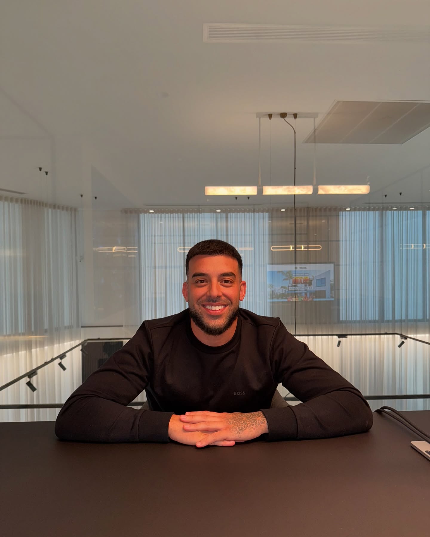 Adrian Portelli sitting with his hands folded on a table