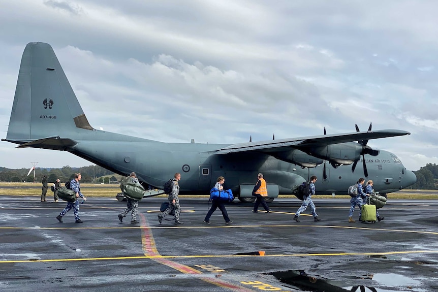 Members of the Australian Defence Force and AUSMAT disembarking from a Hercules aircraft.