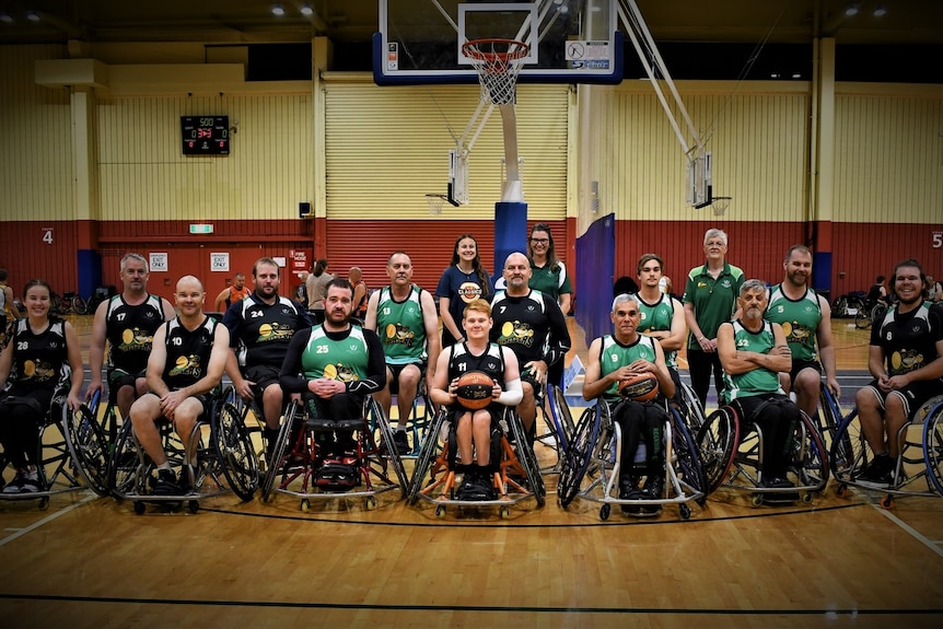 A team of wheelchair basketballers posing for a photo together on a court.