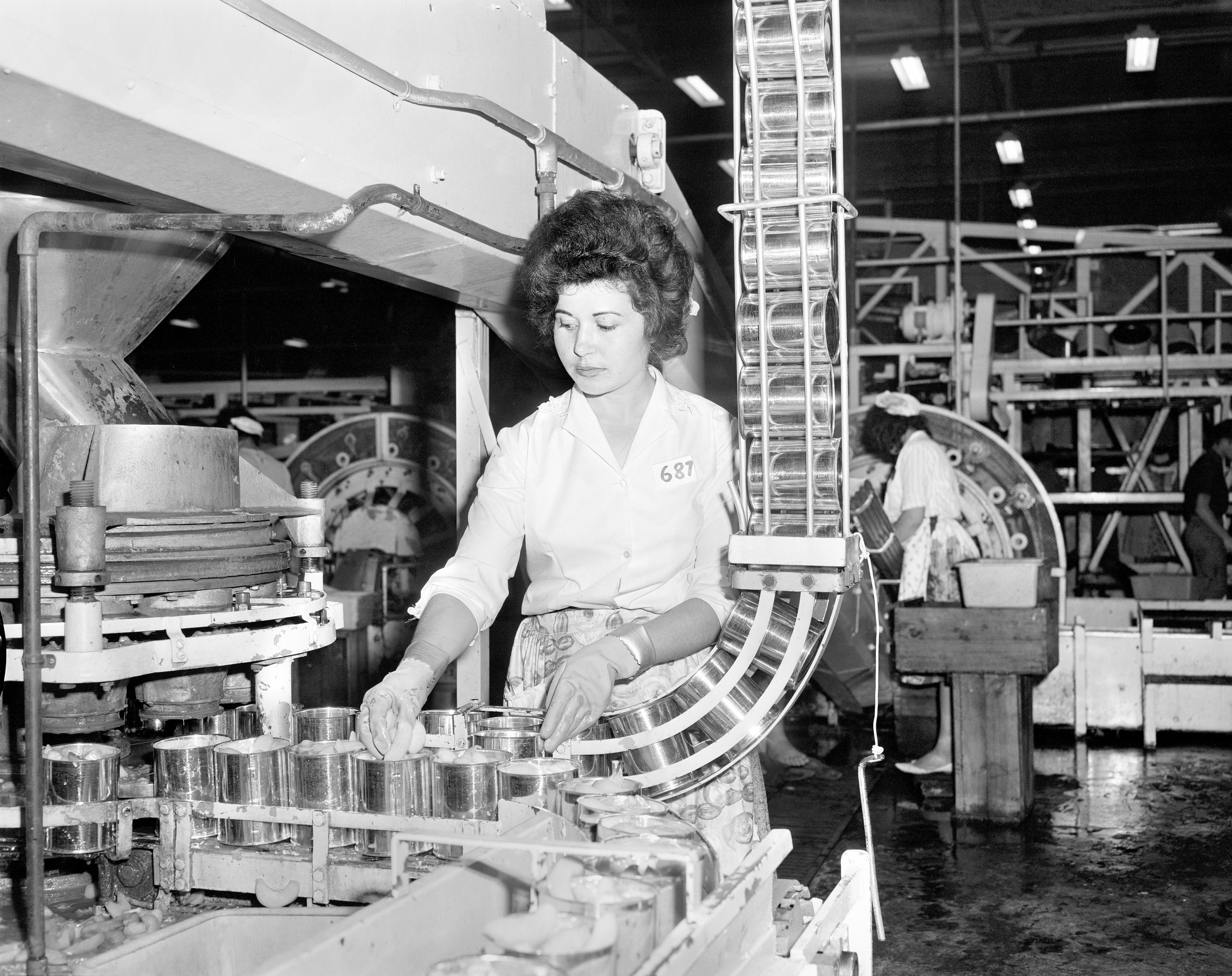 Black and white photo of a Greek woman working on a canning production line.