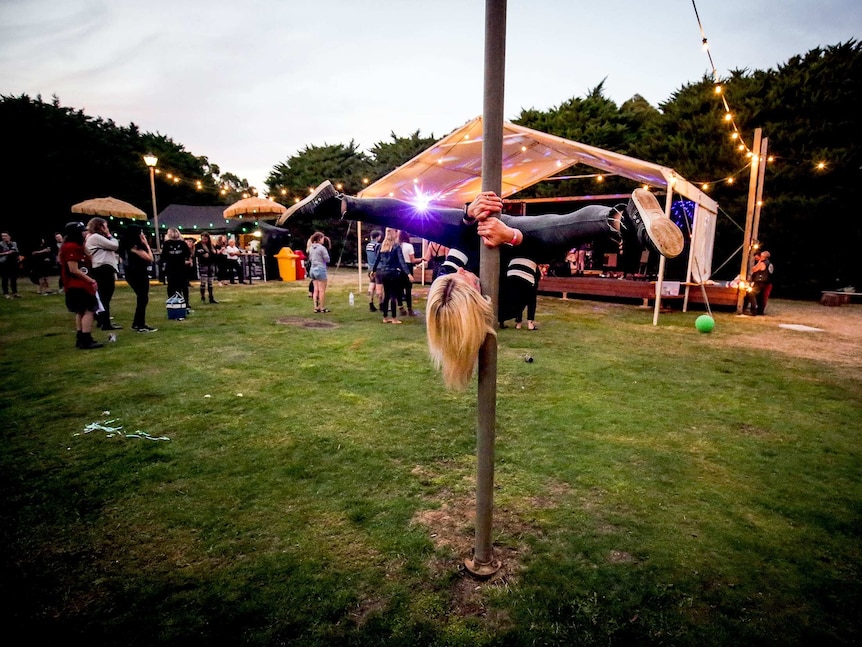 Woman dances on a pole upside down