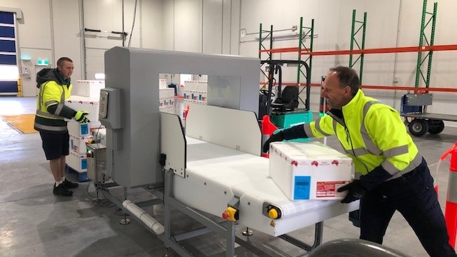 man puts box onto conveyor belt