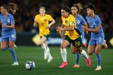 Sam Kerr of Australia's Matildas runs with the ball away from French players.