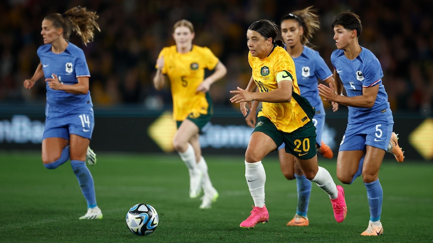 Sam Kerr of Australia's Matildas runs with the ball away from French players.