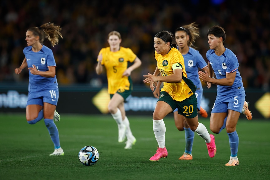 Sam Kerr of Australia's Matildas runs with the ball away from French players.